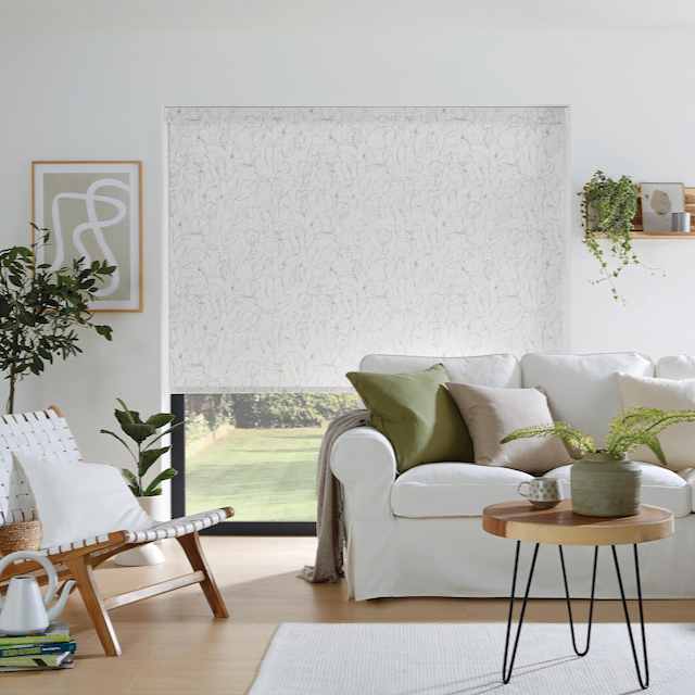 Louvolite Sweet Pea fabric roller blinds hanging on a window in a loung room.
