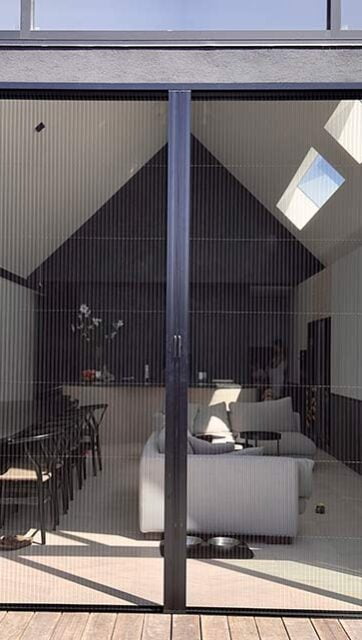 An image of a white outdoor retractable flyscreen covering a large open window.