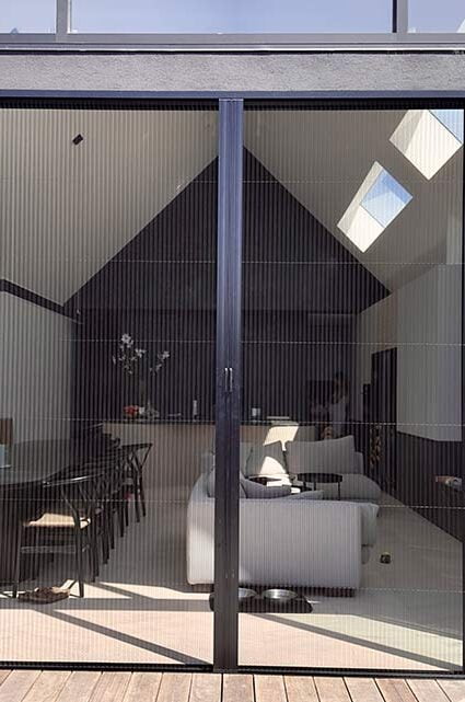 An image of a white outdoor retractable flyscreen covering a large open window.